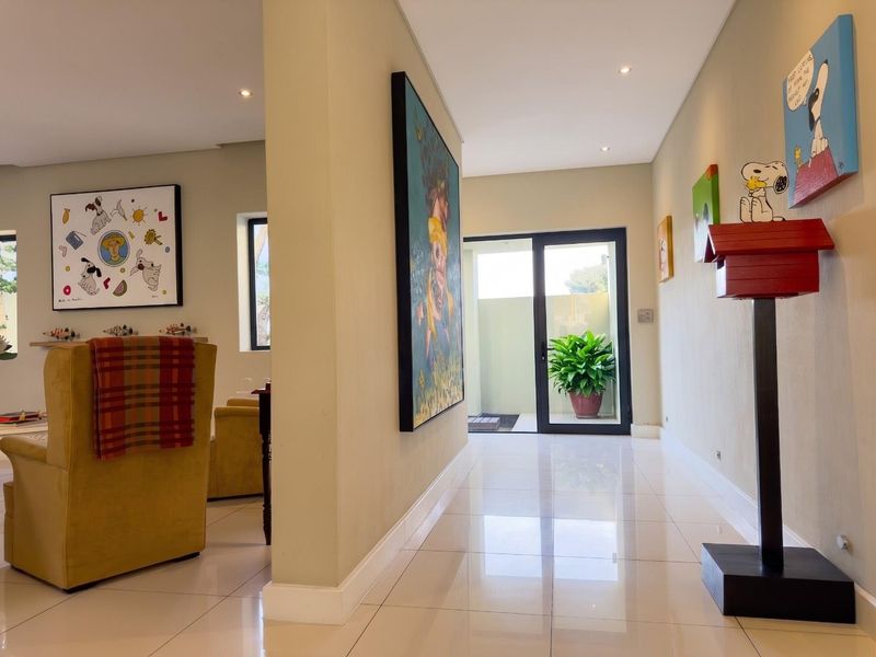 A bright, modern hallway featuring polished tiled flooring, recessed downlighting, and a sliding glass door providing access to an outdoor area.