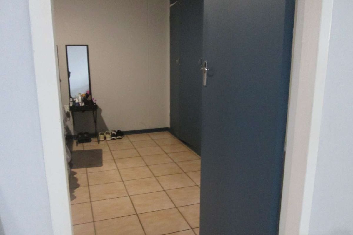 A bedroom featuring tiled flooring and built-in cupboards with dark blue doors, viewed from the doorway.