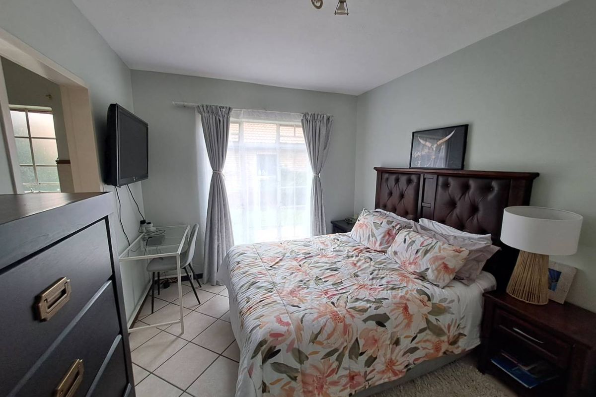 A well-lit bedroom featuring tiled flooring, a window with curtains, and a ceiling-mounted light fixture.