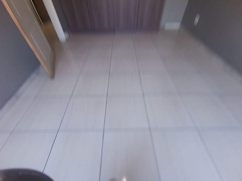 An empty bedroom featuring neutral tiled flooring and built-in cupboards, providing a clean and versatile space ready for personalization.