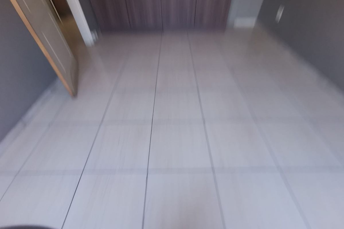 An empty bedroom featuring neutral tiled flooring and built-in cupboards, providing a clean and versatile space ready for personalization.