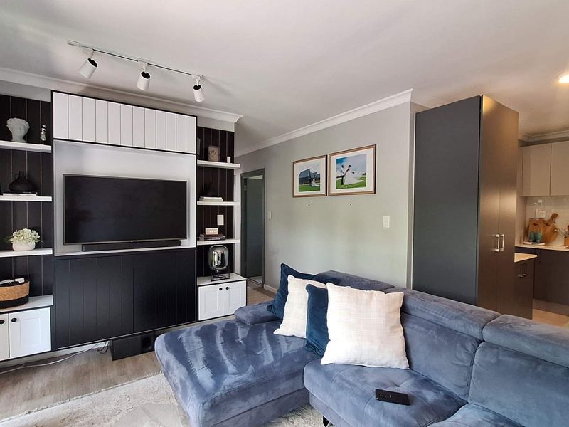 Open-plan living area featuring a modern kitchen with built-in appliances and a custom media wall with integrated shelving and cabinetry.