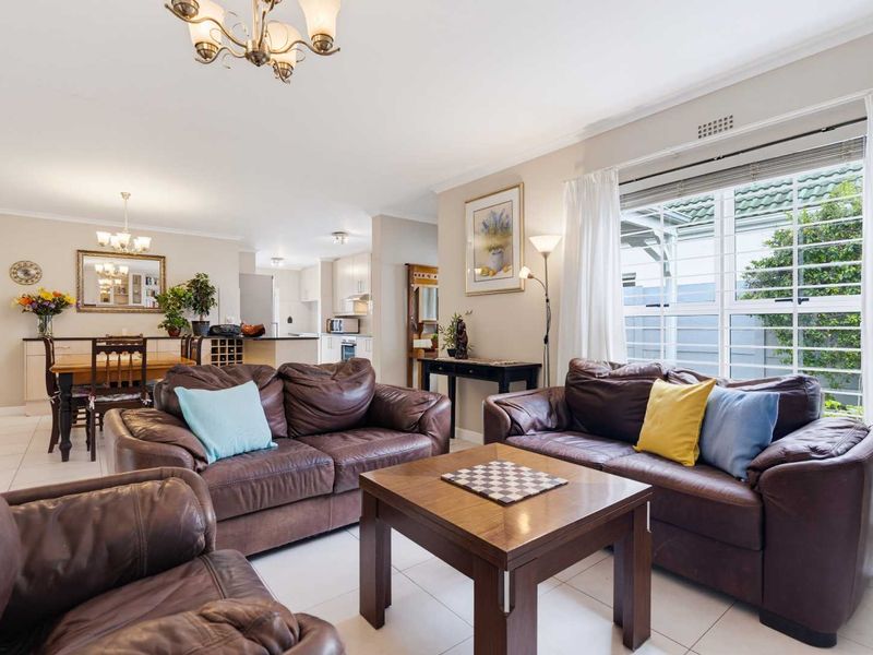 Spacious open-plan living and dining area featuring tiled floors, neutral walls, and a functional kitchen with built-in cabinetry and island.