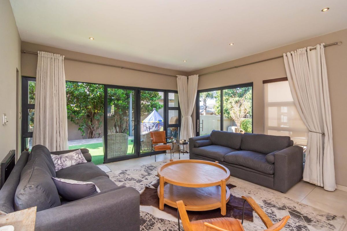 A bright living room featuring large sliding glass doors that provide direct access to the garden and allow for ample natural light.