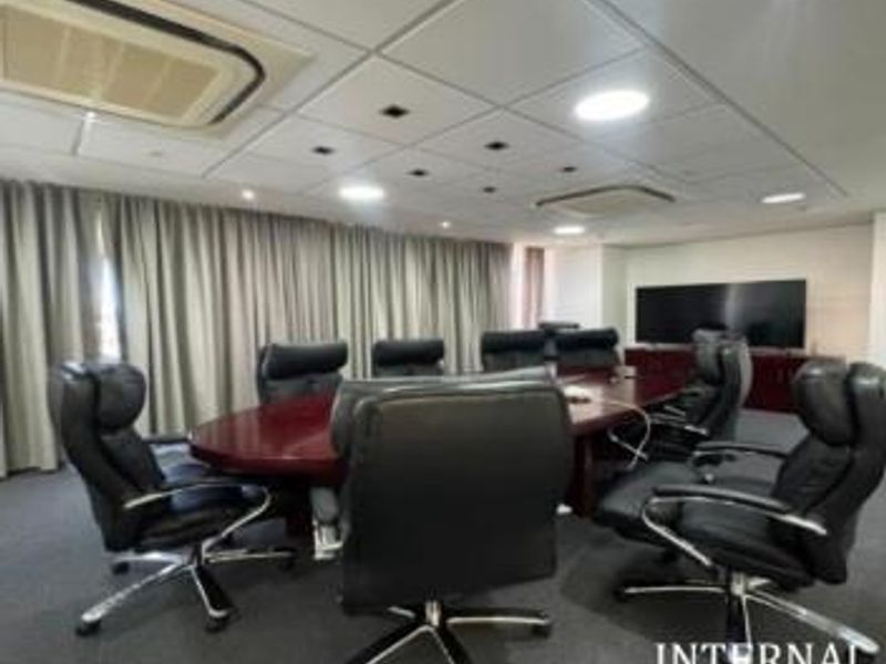 A professional boardroom featuring a large conference table, suspended ceiling with integrated lighting, and ducted air conditioning.