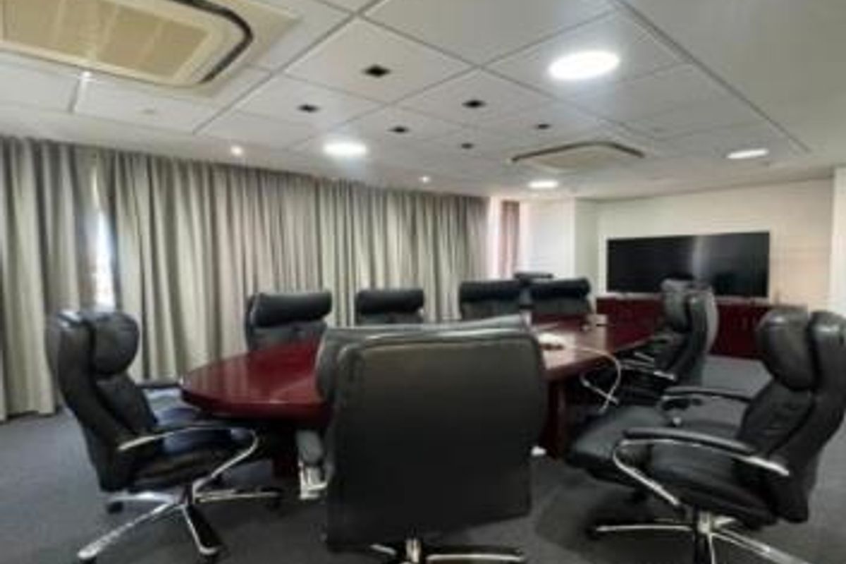 A professional boardroom featuring a large conference table, suspended ceiling with integrated lighting, and ducted air conditioning.