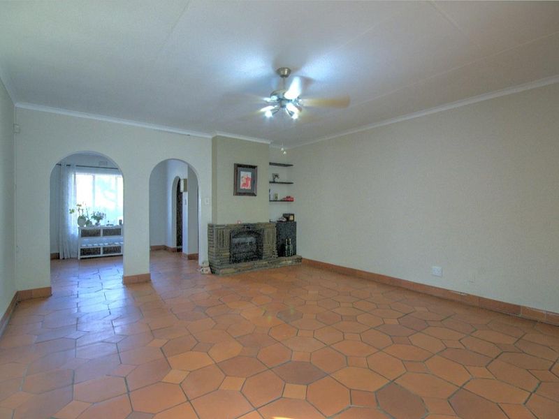 Spacious living room featuring traditional terracotta floor tiles, a central fireplace, and distinctive architectural archways leading to adjacent areas.