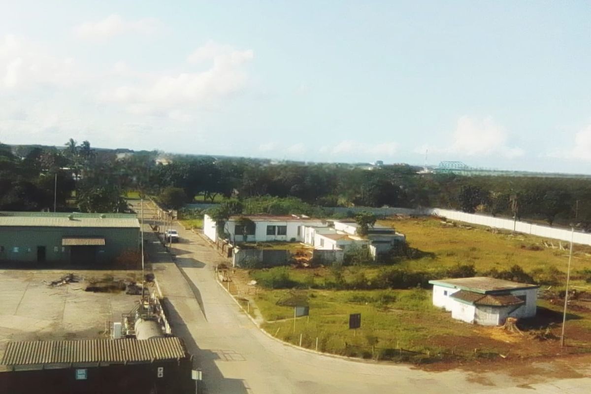 Aerial view of an industrial property site featuring multiple warehouse structures, paved access roads, and surrounding undeveloped land.