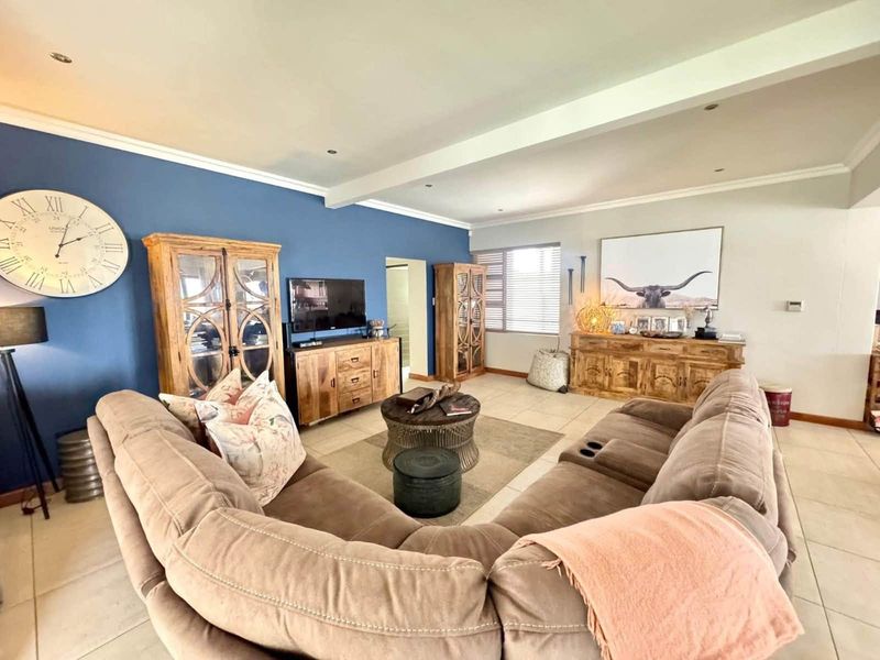 Spacious living room featuring tiled flooring, recessed lighting, and a prominent blue accent wall, creating a comfortable and well-defined lounge area.