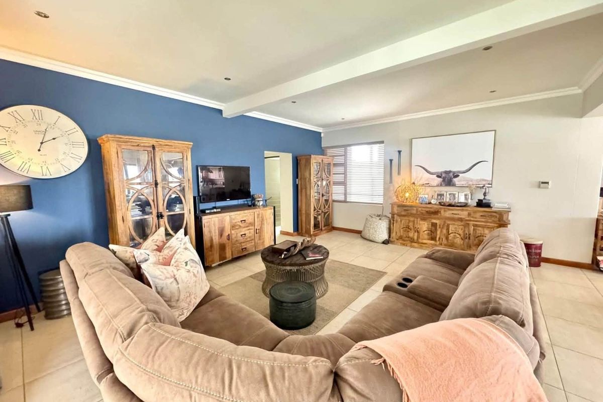 Spacious living room featuring tiled flooring, recessed lighting, and a prominent blue accent wall, creating a comfortable and well-defined lounge area.