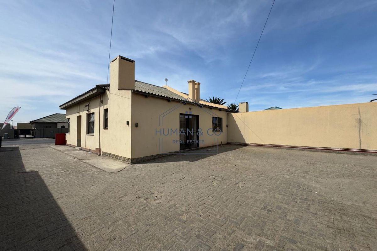 Rear exterior view of the office property featuring a large paved courtyard, perimeter wall, and multiple chimney stacks.