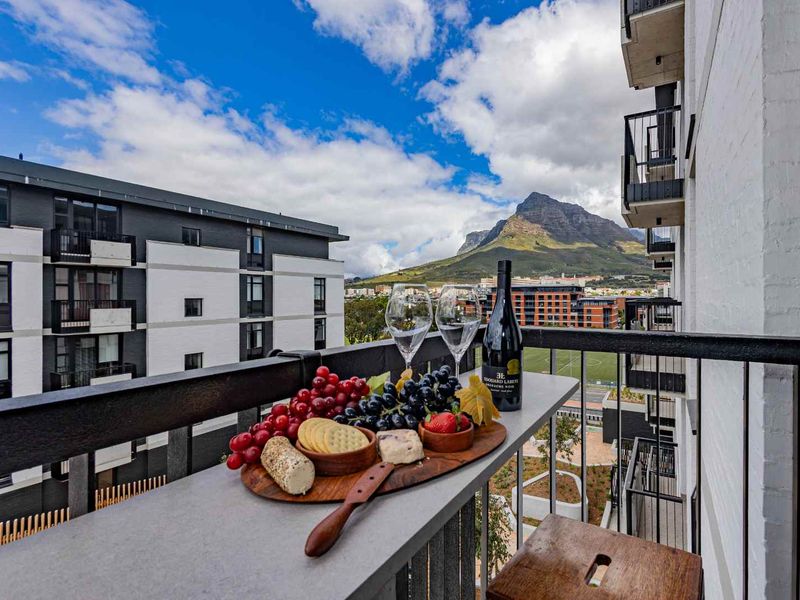 A private balcony featuring a metal railing and elevated views of the surrounding urban landscape and mountain scenery.