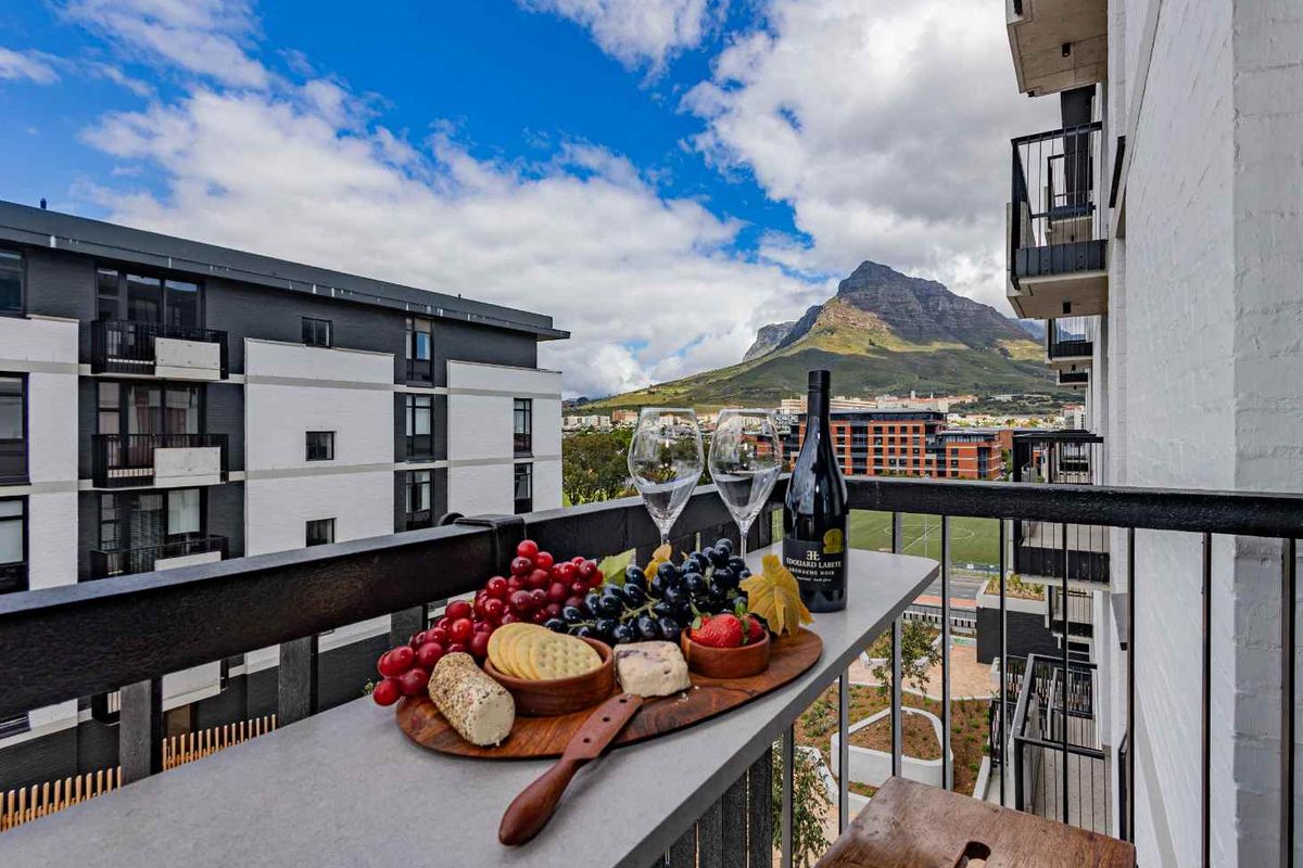 A private balcony featuring a metal railing and elevated views of the surrounding urban landscape and mountain scenery.