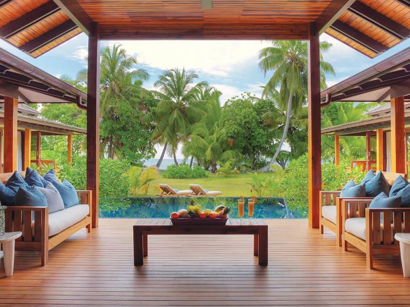 A spacious covered timber deck overlooking a private swimming pool and lush tropical garden, offering a seamless indoor-outdoor living experience.