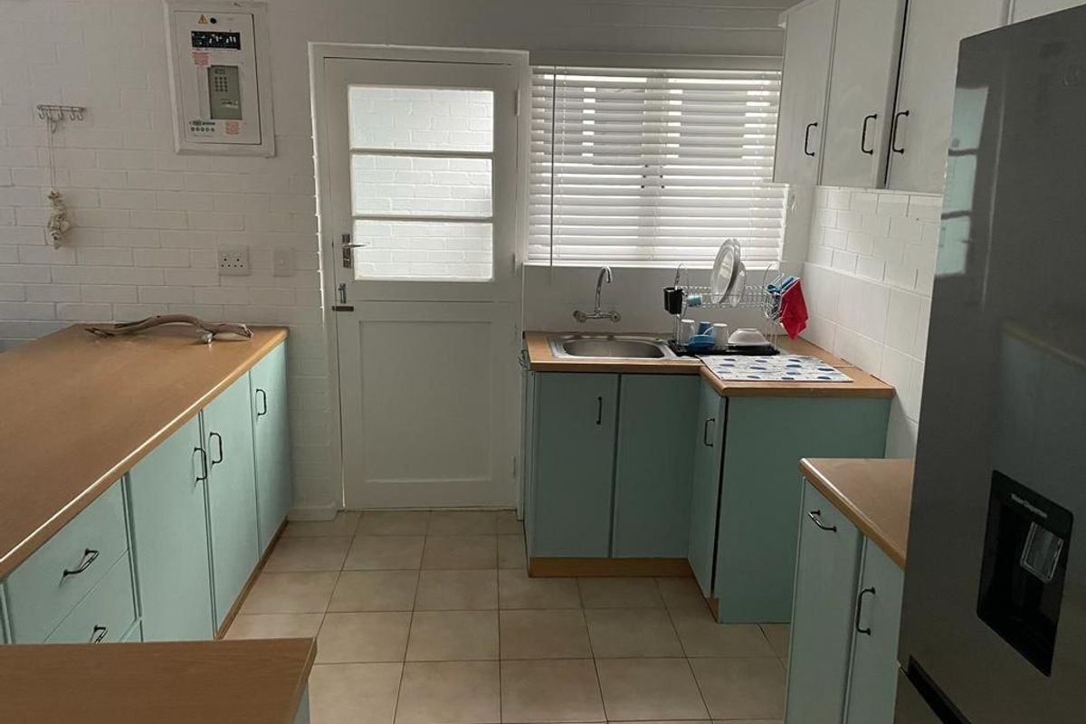 Functional kitchen featuring light blue cabinetry, wood-look countertops, tiled flooring, and a direct exterior access door.