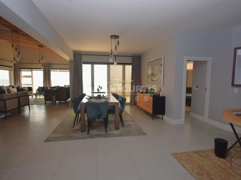 Spacious open-plan living and dining area featuring tiled floors, recessed lighting, and large sliding doors leading to an outdoor space with scenic views.