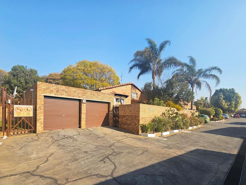 Front exterior view of a face brick townhouse featuring a double garage with roller doors and a paved driveway.