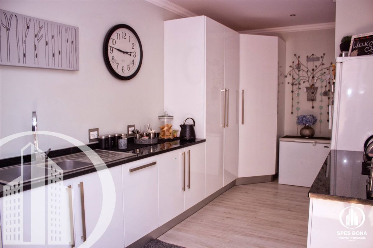 Modern kitchen featuring sleek white cabinetry, contrasting dark granite countertops, and integrated storage solutions in a clean, contemporary layout.