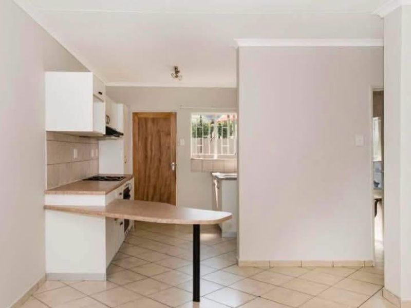A functional kitchen featuring built-in cabinetry, a breakfast bar, and tiled flooring, offering a clean and practical layout for daily use.