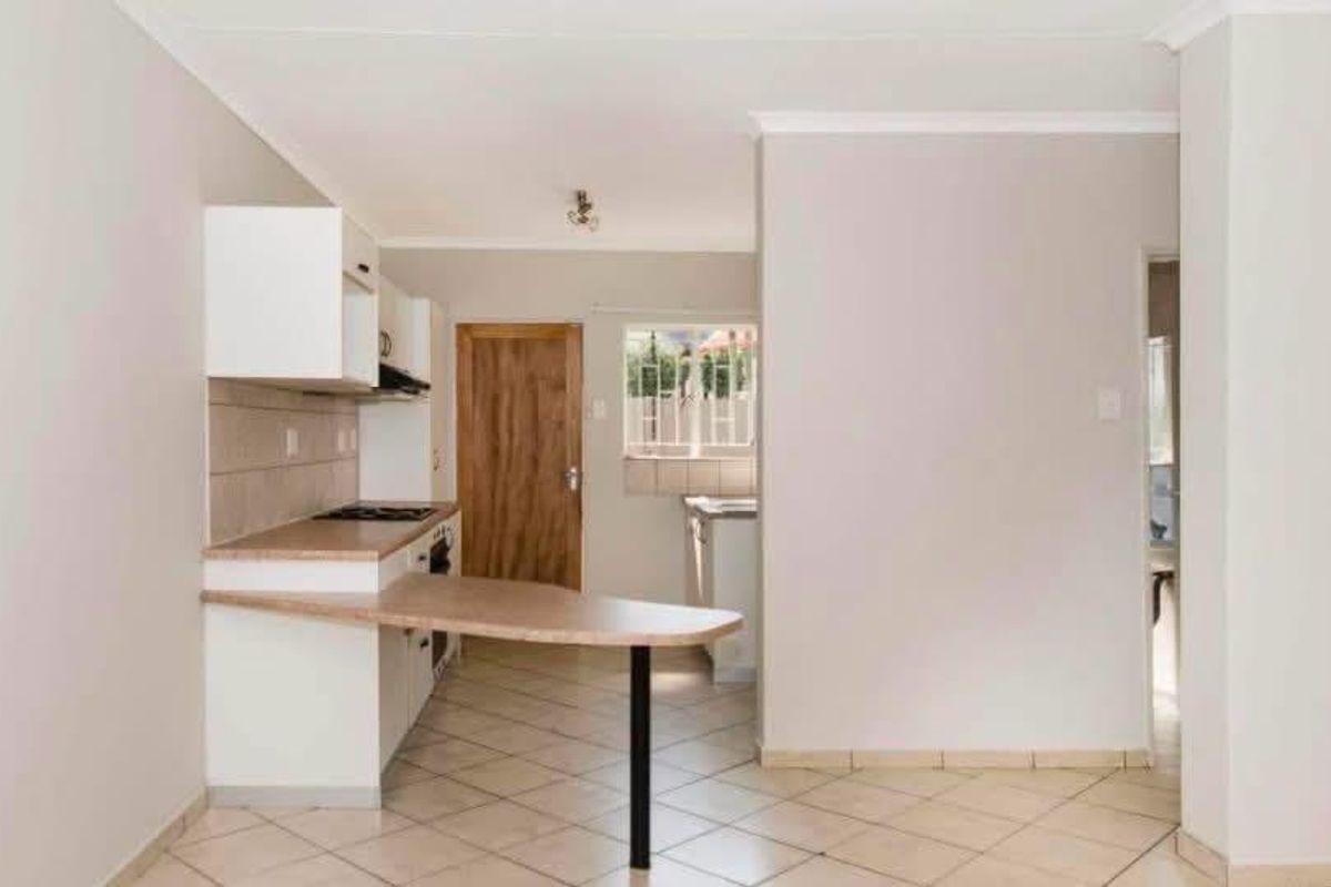 A functional kitchen featuring built-in cabinetry, a breakfast bar, and tiled flooring, offering a clean and practical layout for daily use.