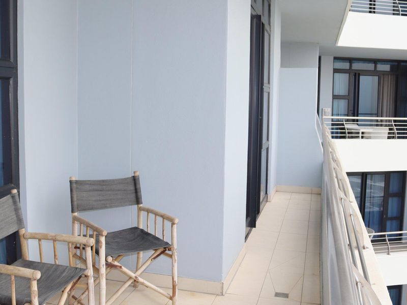 A spacious apartment balcony featuring tiled flooring, metal railings, and direct access to the interior living space.