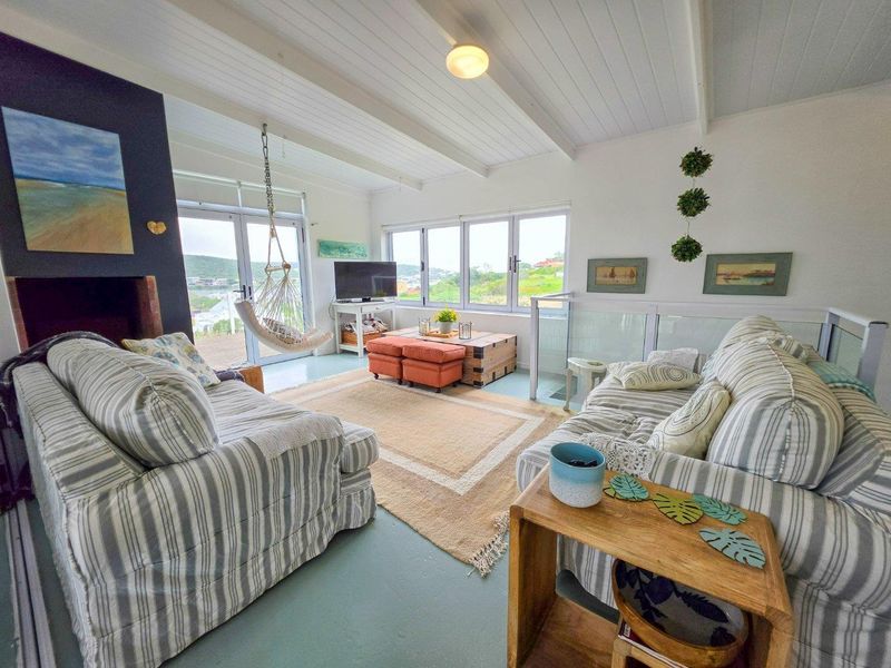 Bright living room featuring a fireplace, exposed beam ceiling, and large windows with glass sliding doors leading to an outdoor area.