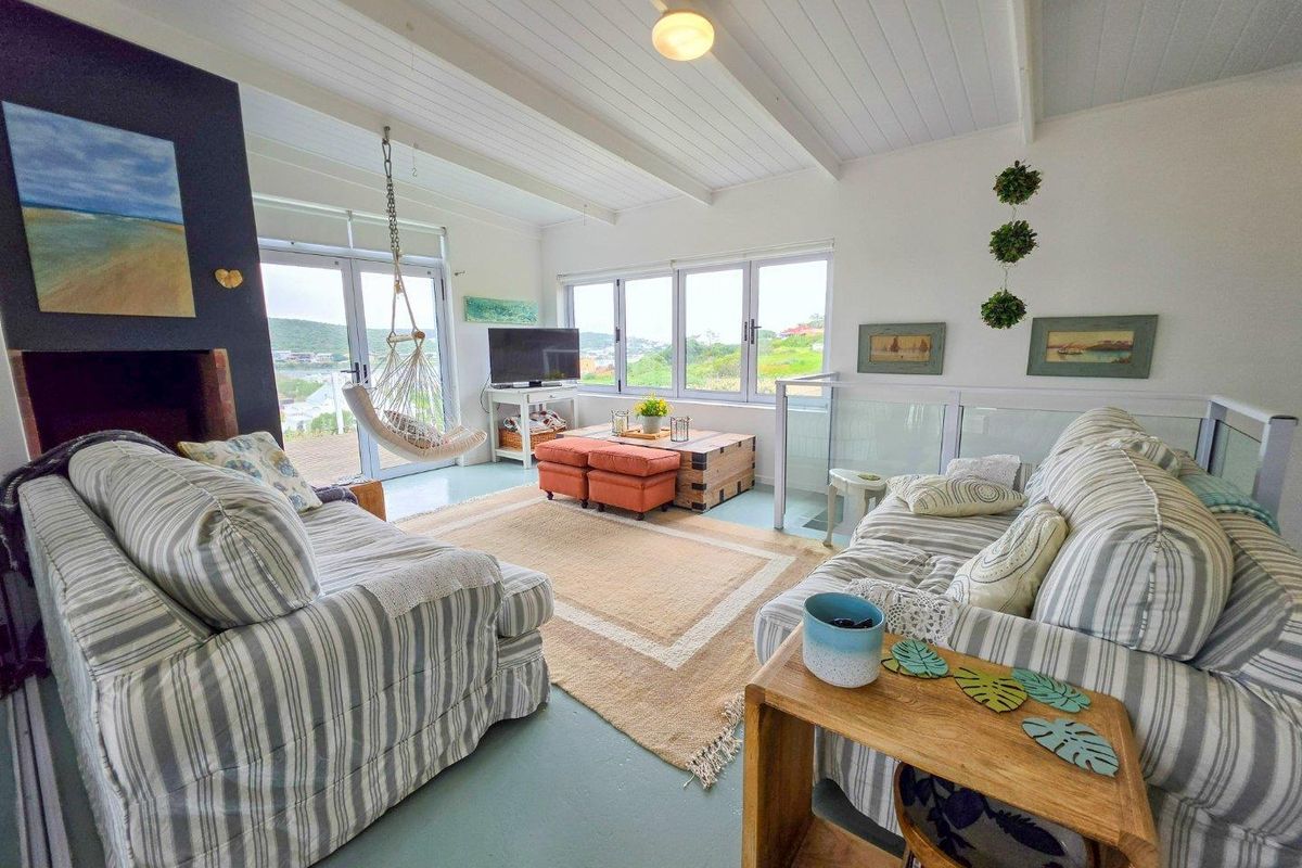Bright living room featuring a fireplace, exposed beam ceiling, and large windows with glass sliding doors leading to an outdoor area.