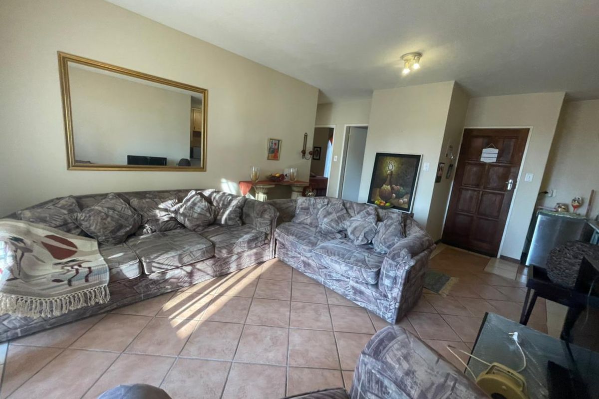 A living room featuring tiled flooring and a wooden entrance door, providing a functional and open living space.