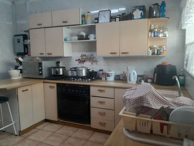 A functional kitchen featuring laminate cabinetry, a gas hob with built-in oven, tiled backsplash, and ceramic floor tiles.