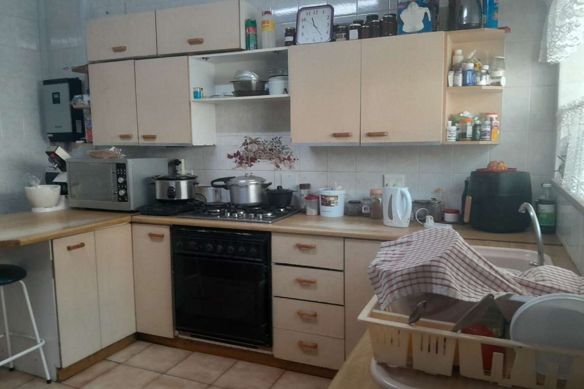 A functional kitchen featuring laminate cabinetry, a gas hob with built-in oven, tiled backsplash, and ceramic floor tiles.