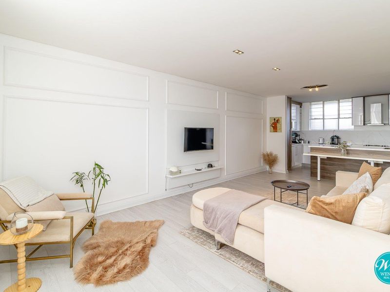 An open-plan living area featuring wainscoting wall detailing, recessed lighting, and a modern kitchen with a central island and sleek cabinetry.