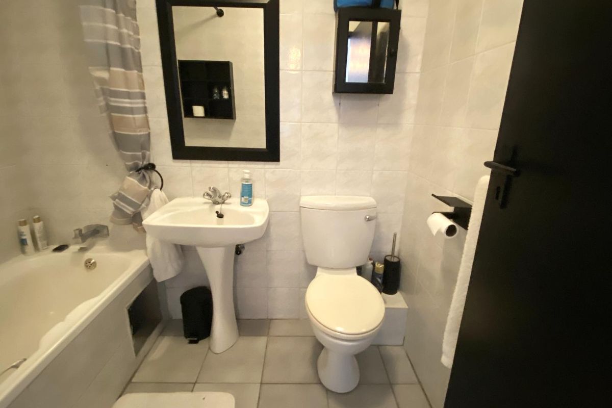 A compact bathroom featuring a pedestal sink, a standard toilet, and a bathtub with a shower mixer.