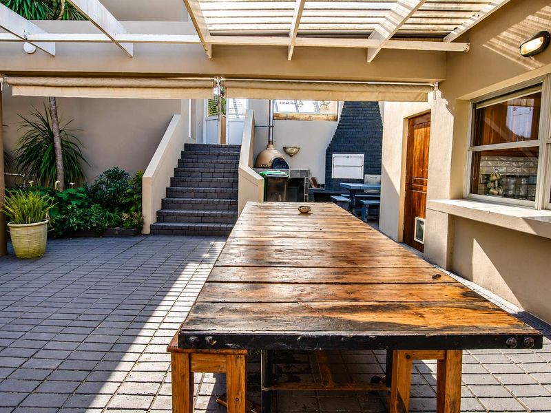 Covered outdoor patio area featuring a built-in braai, pizza oven, paved flooring, and direct access to an external staircase.