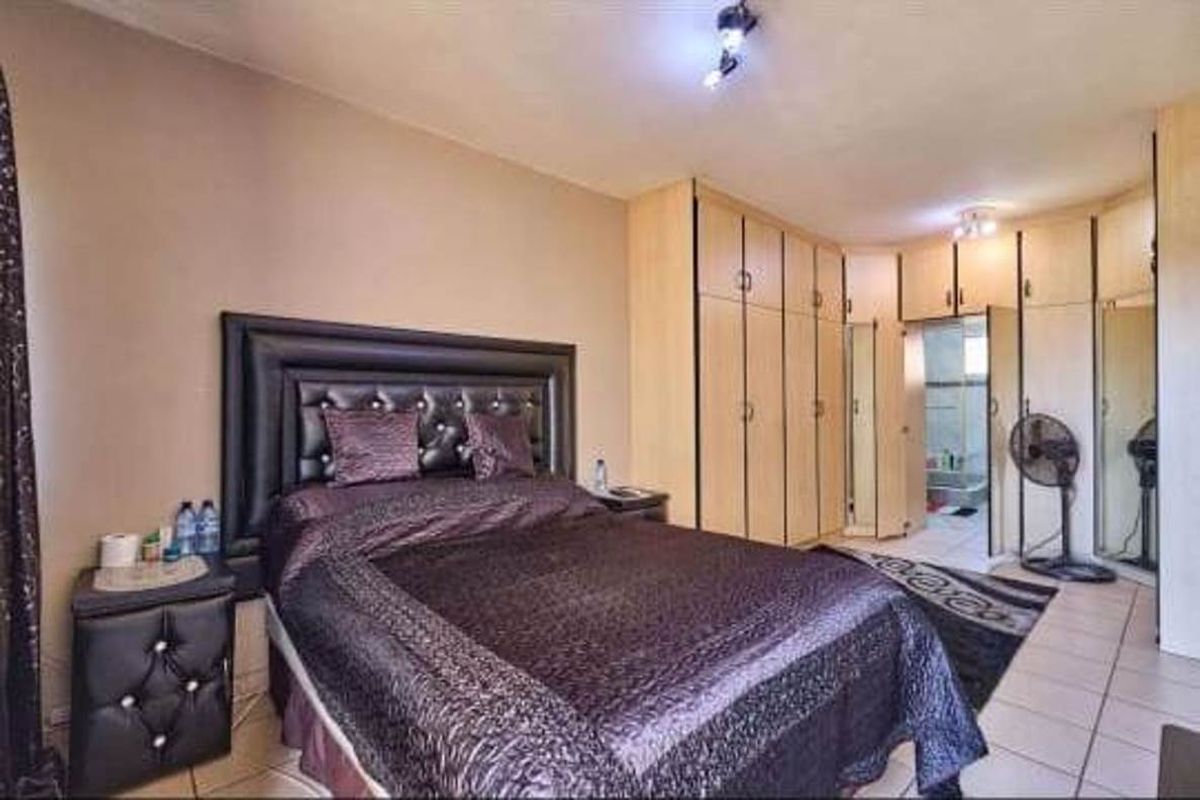 A bedroom featuring built-in wooden cabinetry with integrated mirror panels and an en-suite bathroom access.