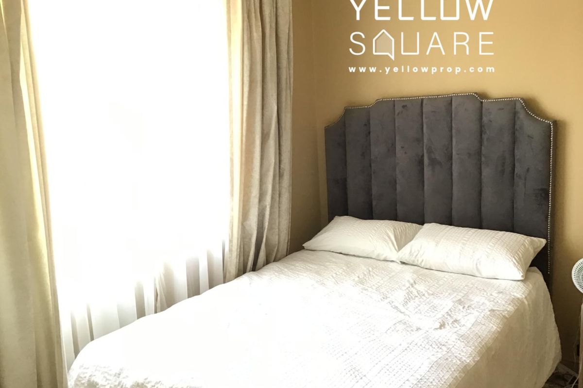 A bedroom featuring a large window with curtains, providing natural light to the space.