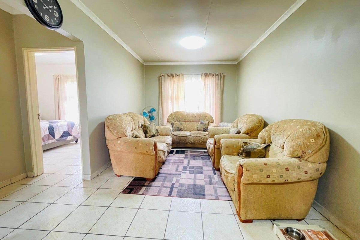 A living room featuring tiled flooring and a view into an adjacent bedroom.