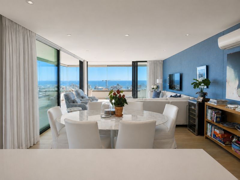 Spacious open-plan living and dining area featuring floor-to-ceiling sliding glass doors, modern timber flooring, and expansive ocean views.