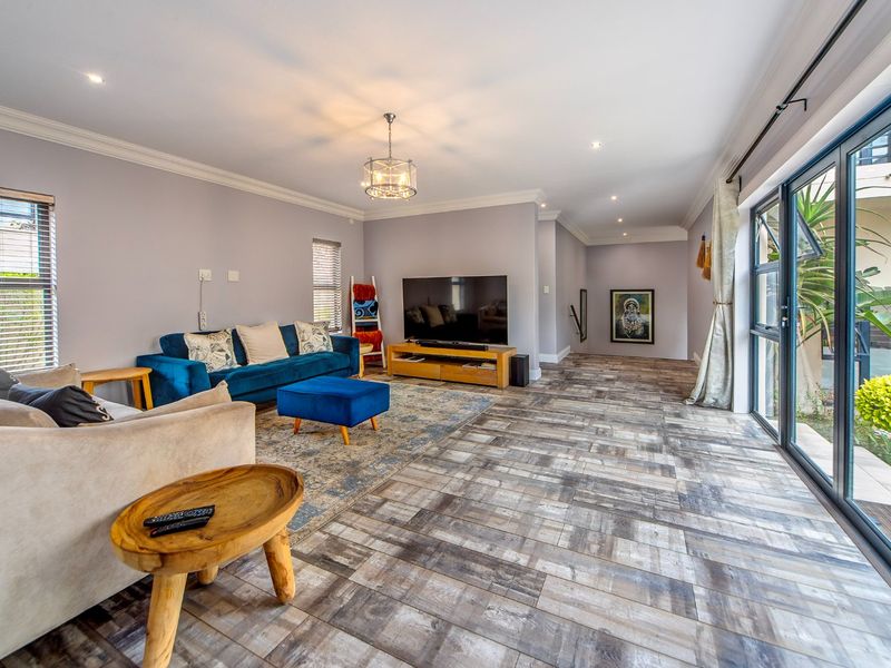 Spacious living room featuring modern tiled flooring, recessed downlighting, crown molding, and large aluminum sliding doors providing seamless access to the outdoor area.