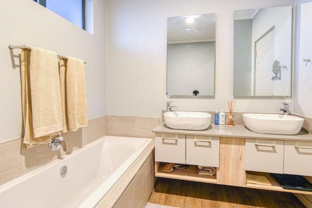 Modern bathroom featuring a built-in bathtub, double vanity with vessel sinks, and wall-mounted mirrors in a clean, well-maintained space.