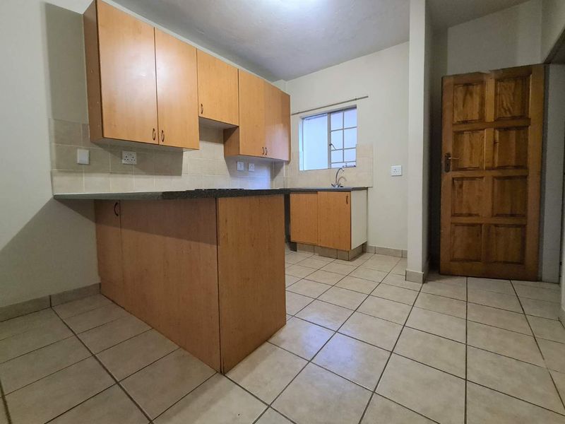 A functional kitchen featuring laminate cabinetry, stone countertops, tiled backsplash, and ceramic floor tiles, offering a clean and practical layout.
