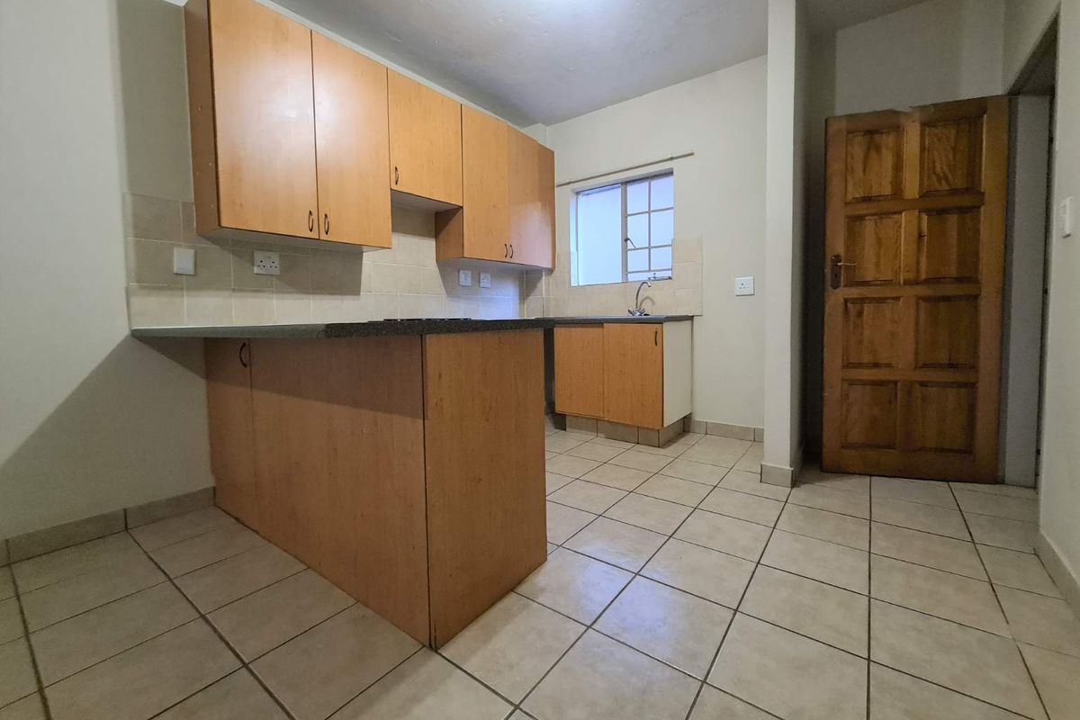 A functional kitchen featuring laminate cabinetry, stone countertops, tiled backsplash, and ceramic floor tiles, offering a clean and practical layout.