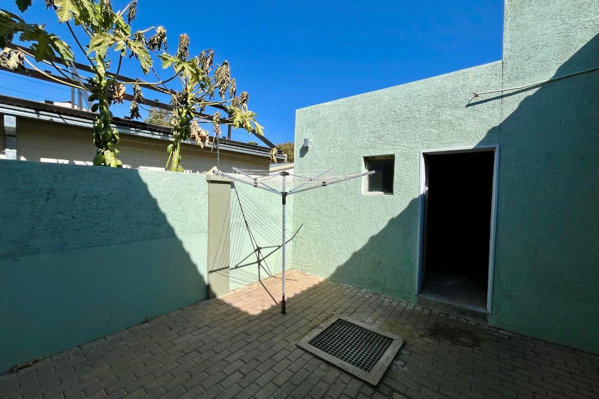 A private exterior courtyard area featuring paved flooring, a secure entrance, and a dedicated space for laundry drying.