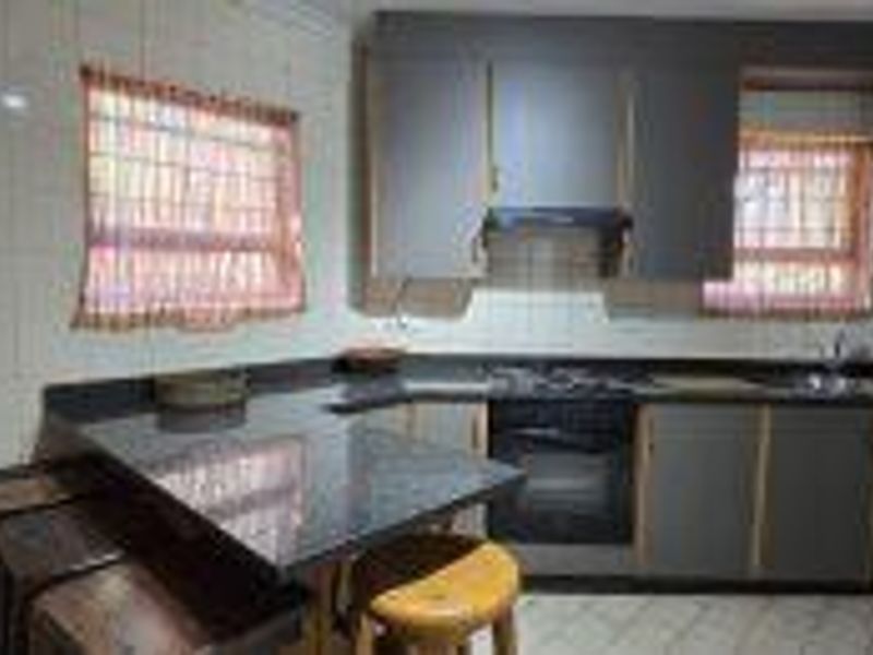 A functional kitchen featuring dark cabinetry, granite countertops, built-in oven and hob, and a tiled backsplash with a breakfast nook area.