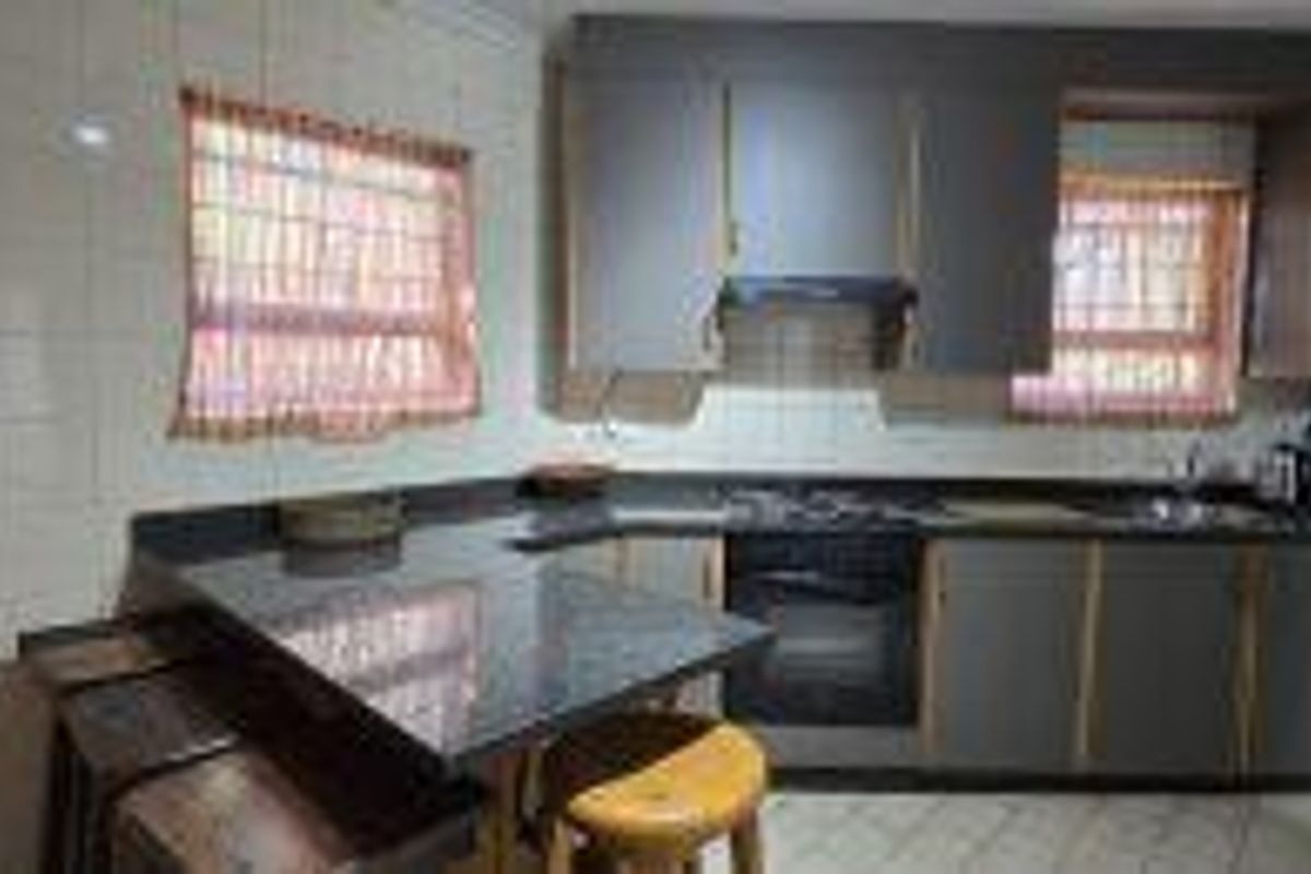 A functional kitchen featuring dark cabinetry, granite countertops, built-in oven and hob, and a tiled backsplash with a breakfast nook area.