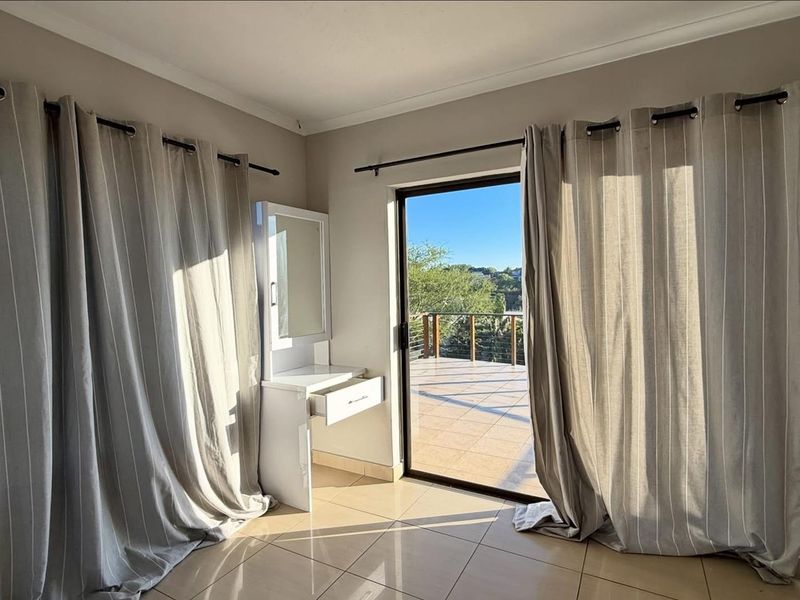 Bright bedroom featuring tiled flooring and a sliding glass door providing direct access to an outdoor balcony.