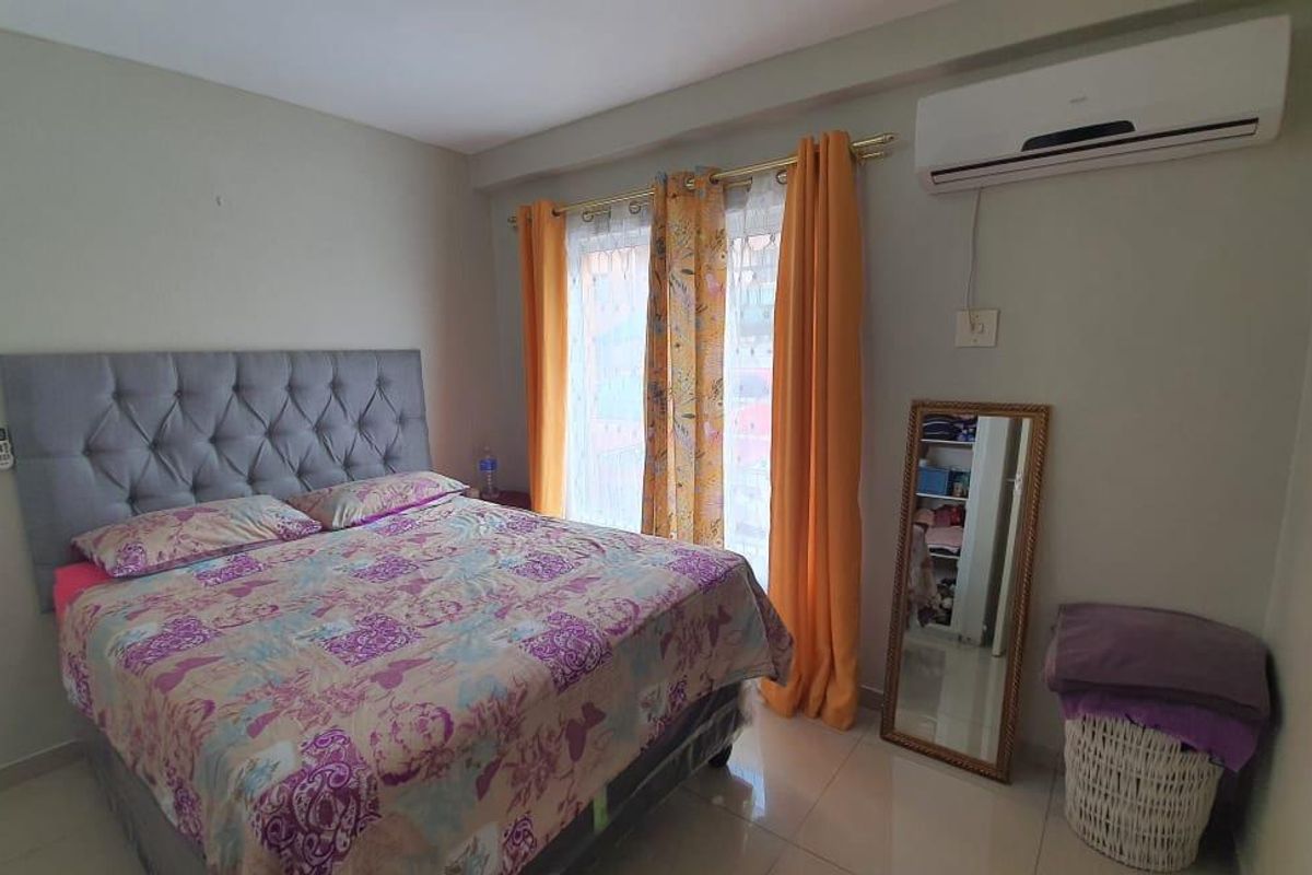 A bedroom featuring tiled flooring and a wall-mounted air conditioning unit, providing a functional and comfortable living space.