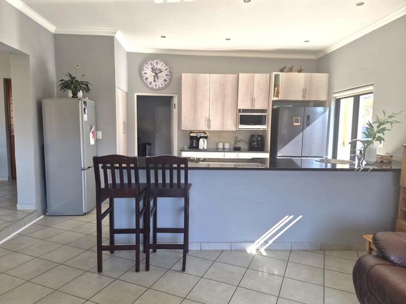A functional kitchen featuring light wood cabinetry, dark granite countertops, a central island, and tiled flooring, offering a clean and practical layout.
