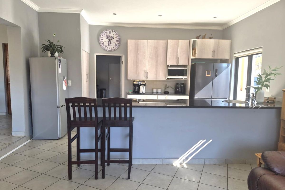 A functional kitchen featuring light wood cabinetry, dark granite countertops, a central island, and tiled flooring, offering a clean and practical layout.