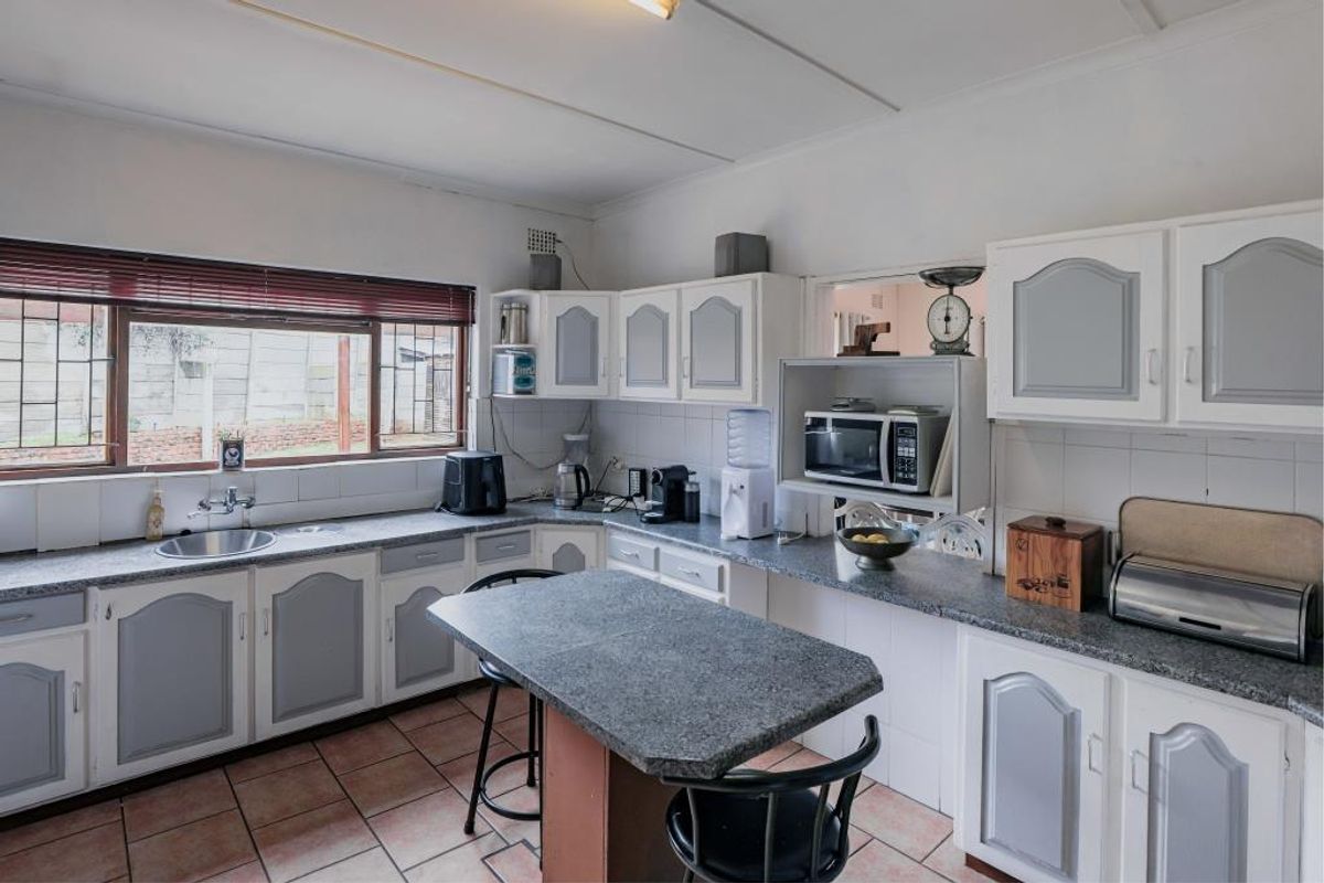 A functional kitchen featuring built-in cabinetry, stone-look countertops, a central island, and tiled flooring with a window overlooking the exterior.