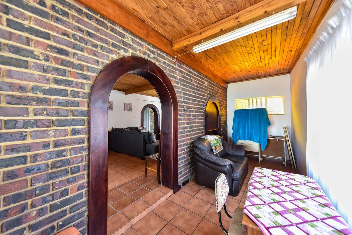 Living area featuring exposed brick walls, arched timber doorways, and a timber-clad ceiling with ceramic floor tiles.